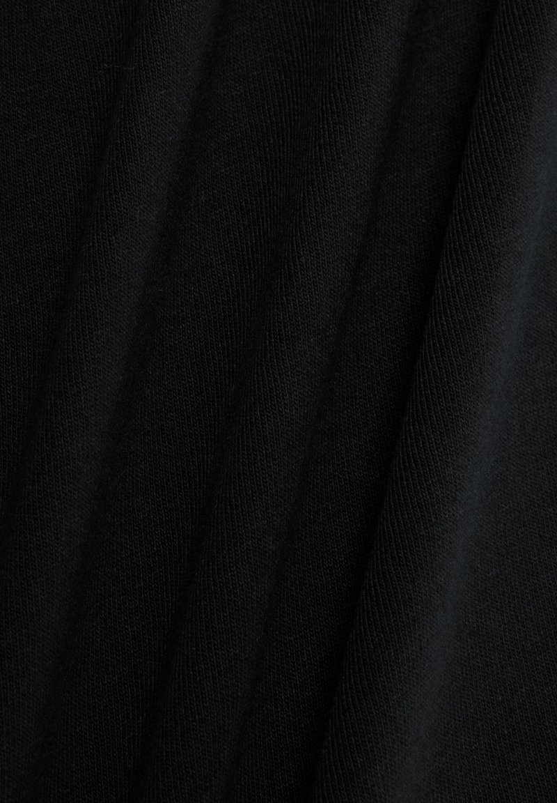 Zwarte stof met een zachte, gestructureerde brei. Plooien creëren diepte en benadrukken een gladde oppervlakte met een egale kleur en consistent patroon doorheen.