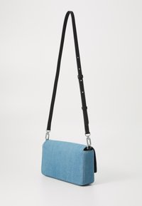 Plava traper crossbody torba pravokutnog oblika, s crnim podesivim remenom, srebrnim detaljima i čistim šavovima koji osiguravaju glatku teksturu.