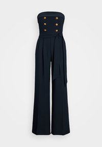 Navyn sinivärvi, ilmaoluline jumpsuit, mis on valmistatud siledast kangast, millel on sobiv bodice, viis kuldset nööpi, laiad püksid ja seotud vöö.