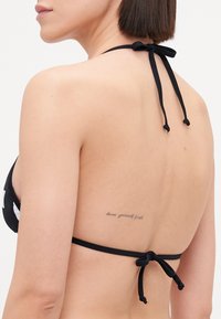 Čierny bikiny top s viazaním na krku, s hladkou textúrou. Na chrbte je viditeľné tetovanie s citátom, ktoré dodáva dizajnu detaily.