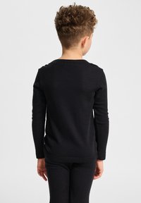Schwarzes Langarmoberteil aus einem weichen Material, mit Rundhalsausschnitt und schmaler Passform, von hinten an einem Kind gezeigt.