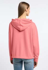 Roze hoodie met een ontspannen pasvorm, lange mouwen en een ronde zoom, gemaakt van zachte stof. Voorzien van een trekkoord capuchon en een minimalistisch ontwerp.