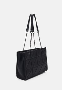 Černá obdélníková kabelka s geometrickým prošíváním, s dvojitými řetízkovými a koženými ramenními popruhy, stojící na jednobarevném bílém pozadí.