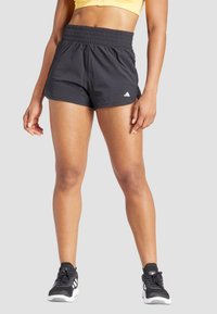 Melni sporta šorti ar elastīgu jostasvietu, viegla auduma un sānu šķirbēm. Apvienoti ar melnas un baltas sporta apaviem.