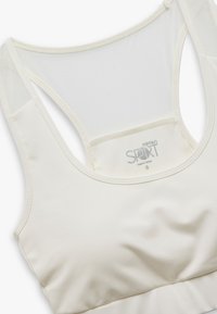 Lichtbeige sportbeha met een gladde stof, racerback-ontwerp en zachte mesh panelen. Voorzien van een label met het merk "Koton SPORT" en maat S.