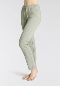 Hellgrüne Jogginghosen mit einem elastischen Bund, Kordelzug und gesticktem Logo. Schmaler Schnitt mit umgeschlagenen Bündchen und glatter Textur.
