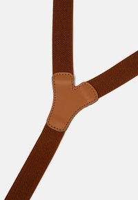 Brown fabric suspenders with a textured, woven pattern. Features a smooth, tan leather Y-shaped connector with stitched edges.