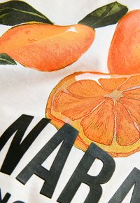 Tessuto di cotone con sfondo bianco presenta illustrazioni vivaci di frutti arancioni. Testo nero in basso con la scritta "NARANJA." Dettagli testurizzati migliorano la visibilità.