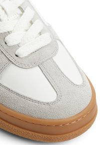 Szare zamszowe sneakersy z białymi skórzanymi akcentami, płaskimi białymi sznurówkami i fakturowaną gumową podeszwą. Posiadają zaokrąglony czubek i przeszycia.
