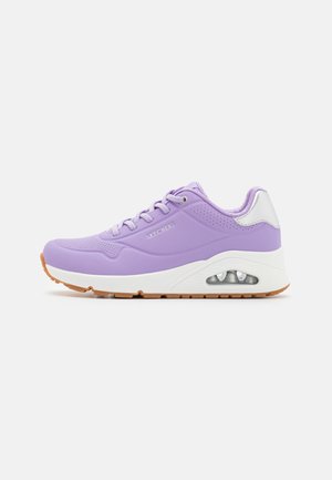 Scarpe da ginnastica viola con una texture liscia, dettagli bianchi, una suola imbottita con una bolla d'aria visibile e una tomaia perforata.