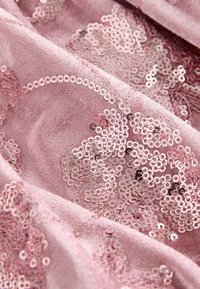Rosa stof med en blød tekstur, prydet med et blomstermønster af rosaguld pailletter i forskellige størrelser, hvilket skaber glans og visuel interesse.