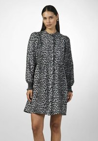 Mekko, jossa on leopardikuosi, pitkät hihat, napitus edessä ja muotoiltu vyötärö. Valmistettu pehmeästä kankaasta, jossa on valuva hame.