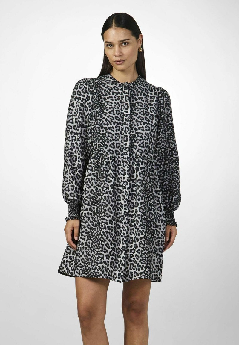 Mekko, jossa on leopardikuosi, pitkät hihat, napitus edessä ja muotoiltu vyötärö. Valmistettu pehmeästä kankaasta, jossa on valuva hame.