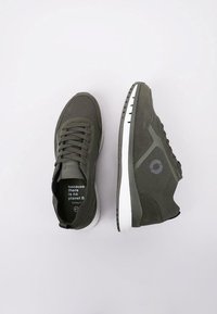 Baskets vert foncé en mesh et suède, avec une semelle blanche et des accents gris clair. Comprend un texte imprimé sur la semelle intérieure.