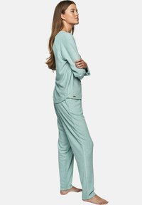 Ensemble de pyjama bleu clair en tissu doux et texturé. Haut à manches longues avec une coupe décontractée et un pantalon assorti avec une taille élastique.