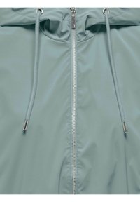 Veste imperméable bleu clair avec fermeture éclair argentée et cordons assortis avec embouts métalliques sur la capuche.