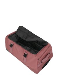 Borsa da viaggio in tessuto rosa con interno nero, doppi manici di trasporto e chiusura con zip. Presenta due fibbie sulla parte anteriore e una tasca laterale.