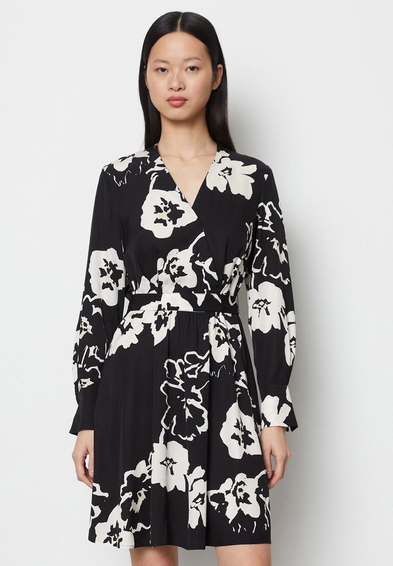 Schwarzes Kleid mit weißem Blumenmuster, Wickeldesign, V-Ausschnitt und langen Ärmeln. Verfügt über einen Taillengürtel und gerafftes Rockdetail.