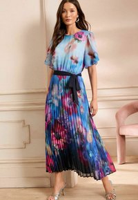 Ráncolt maxi ruha, amely virágmintával rendelkezik kék, rózsaszín és lila árnyalatokban. Rövid, áttetsző ujjakkal és fekete derékszíjjal készült.