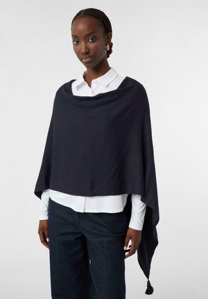 Dunkelgrauer Poncho aus weichem Stoff, mit drapiertem Design, runder Halslinie und dekorativem Quasten am Saum. Tragen über einem weißen Hemd.