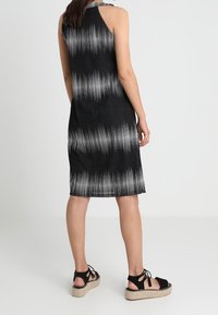 Schwarz-weiße gestreifte ärmellose Kleid mit geradem Schnitt, strukturiertem Stoff und knielangem Saum, kombiniert mit schwarzen Espadrilles.