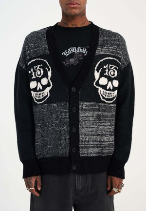 Gebreide cardigan met een zwart en grijs patroon en witte schedelmotieven, knopen sluiting, en ribbelboorden en zoom.