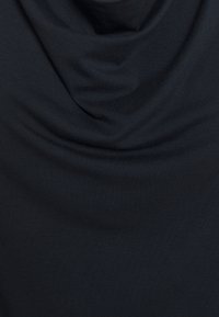 Top de cuello vuelto en tela azul marino oscuro, con una textura suave y lisa, diseño drapeado y acabado acanalado, creando un volumen sutil.