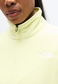 Φούτερ από απαλό κίτρινο φλις με ψηλό γιακά, κλείσιμο με μισό φερμουάρ και λευκό κεντημένο λογότυπο στο στήθος. Λείο υλικό, casual σχεδιασμός.