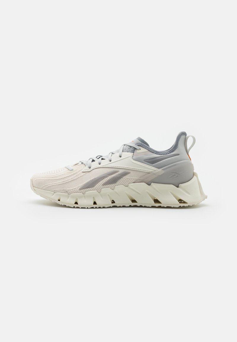 Lightweight athletic shoe featuring a breathable mesh upper in off-white and gray, with a thick, sculpted sole and textured accents.