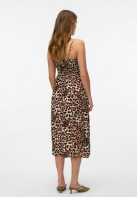 Midi haljina s uzorkom leopard, tankim trakama, naboranim leđima i glatkim materijalom. Nošena s zelenim sandalama na petu i ima ležeran kroj.
