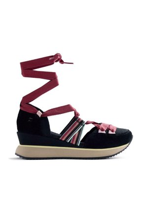 Sandale compensée noire avec des sangles roses qui s'enroulent autour de la cheville, des bandes élastiques multicolores sur le côté, et une semelle beige avec une bande de roulement noire.