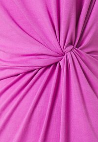 Tessuto rosa con una consistenza morbida, caratterizzato da pieghe arricciate e un dettaglio attorcigliato al centro, che crea un effetto visivo dinamico.