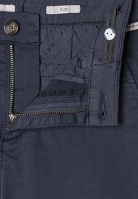 Mornarsko modri slim-fit kavbojke z zadrgo, gumbom za zapiranje in teksturirano notranjo oblogo s tiskano blagovno znamko. Gladko blago.