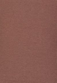 Tecido canelado em uma cor terracota quente com uma superfície texturizada, apresentando linhas verticais por todo o lado. Material suave e ligeiramente elástico.