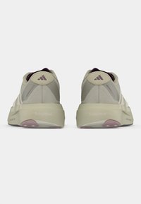 Αθλητικά παπούτσια ανοιχτό γκρι με υφή στην επάνω επιφάνεια, χοντρή κρεμ σόλα και μοβ λεπτομέρειες. Διαθέτει τρεις λευκές ρίγες και λογότυπο στη φτέρνα.