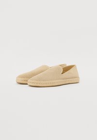 Scarpe slip-on beige con tomaia in rete, suola in juta intrecciata e punta arrotondata. Superficie testurizzata e design minimalista.