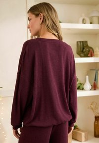 Bordeaux ribbet sweater med en afslappet pasform, brede ærmer og rund halsudskæring. Bagsiden har en subtil tekstur og falder blødt.