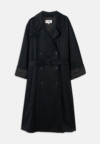 Svart trenchcoat med dubbelknäppning, breda slag, bältad midja och kontrasterande satinärmar. Slät textur.