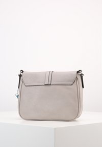 Šedá kožená kabelka přes rameno s klopou, se dvěma vertikálními švy na přední straně a černými kovovými detaily. Hladký povrch.