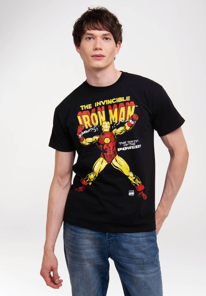 Schwarzes Baumwoll-T-Shirt mit einem bunten Iron Man-Graphic in Rot, Gelb und Weiß; kurze Ärmel und runder Ausschnitt. Getragen mit blauen Jeans.