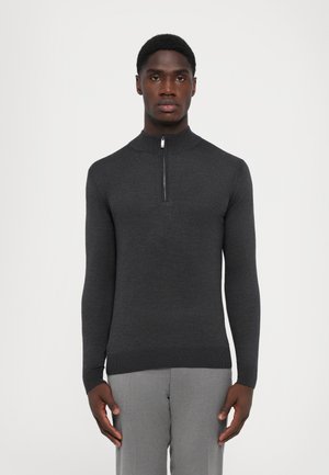 Suéter de punto gris oscuro con un alto cuello y una cremallera de cuarto de longitud. Las mangas largas y los puños acanalados destacan su diseño ajustado.