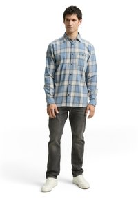 Blauwe geruite overhemd met witte en bruine accenten, van een katoenmix, met lange mouwen, borstzak, gecombineerd met donkere jeans en witte sneakers.