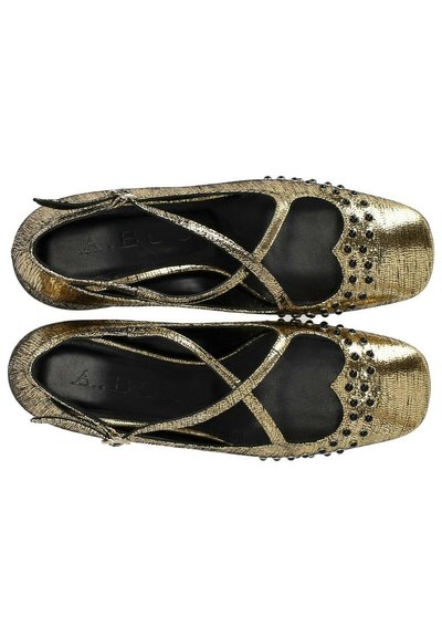 Ballerine metalliche dorate con cinghie incrociate, punta quadrata, finitura testurizzata e borchie decorative nere lungo il bordo della punta e dei lati.