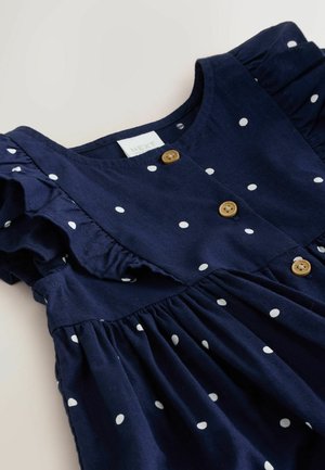 Granatowa bawełniana sukienka w białe kropki, z falbanami na rękawach, okrągłym dekoltem oraz zapięciem na drewniane guziki z przodu.