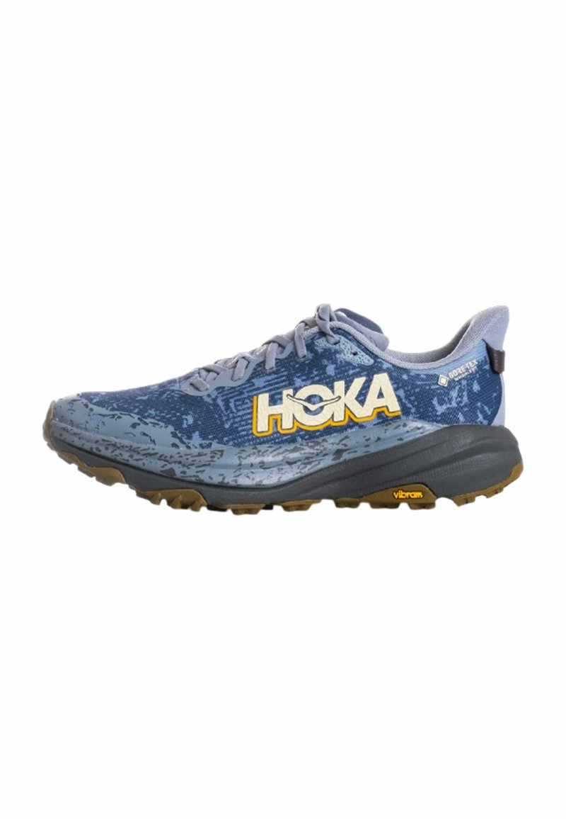 Scarpa da trail running Hoka blu e grigia con Gore-Tex e suola Vibram, tomaia decorata e logo giallo sul lato.