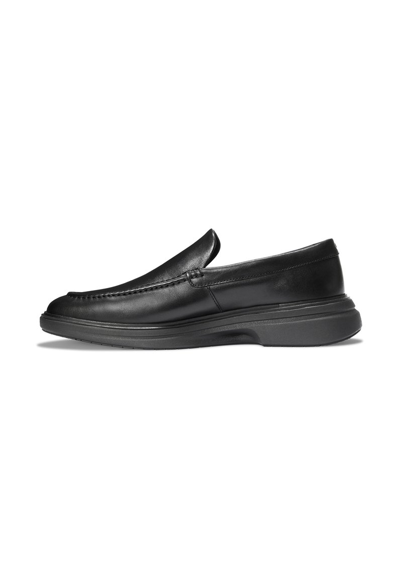 Mocasines de cuero negro sin cordones con tacón bajo y punta redonda, vista de perfil lateral sobre fondo blanco.