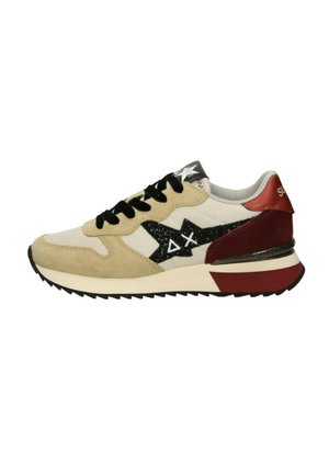 Zapatilla deportiva beige y blanca con cordones negros, logotipo de estrella negra con símbolos blancos y detalles rojos en el talón y la suela.