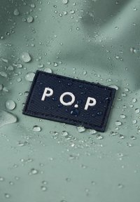 Waterafstotende stof in gedempt groen met een textuur navy patch gemarkeerd "P.O.P." en druppels op het oppervlak, wat de waterdichte kwaliteit benadrukt.