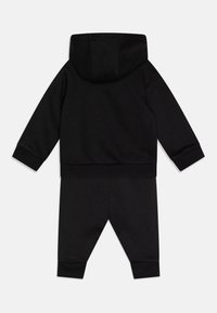 Tuta in cotone nera con felpa con cappuccio, polsini elasticizzati e pantaloni coordinati, entrambi con una texture morbida e una vestibilità comoda.