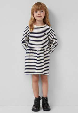 Gestreepte lange mouw jurk in crème en marineblauw met een geraffineerde taille, voorzien van een kleine dieren borduur. Zwarte enkellaarsjes maken de outfit compleet.